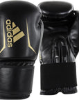 Black boxing gloves with gold Adidas logo on a black background