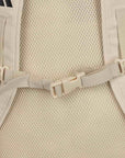 close up image of back side of tan backpack, showing the buckled straps
