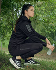 woman in nature wearing adidas branded jacket and pants black and grey