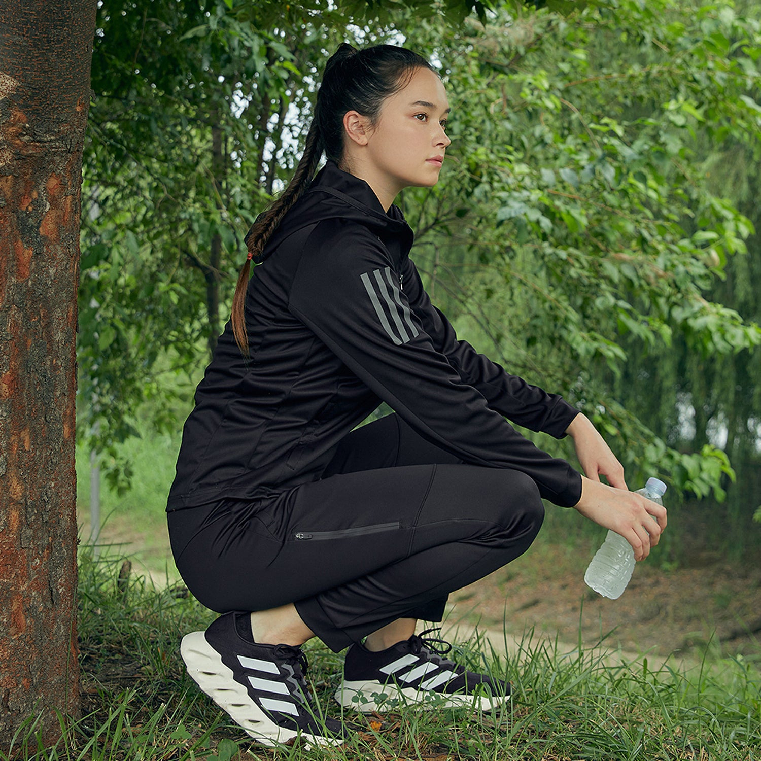 woman in nature wearing adidas branded jacket and pants black and grey