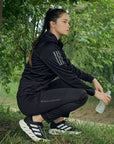 woman in nature wearing adidas branded jacket and pants black and grey
