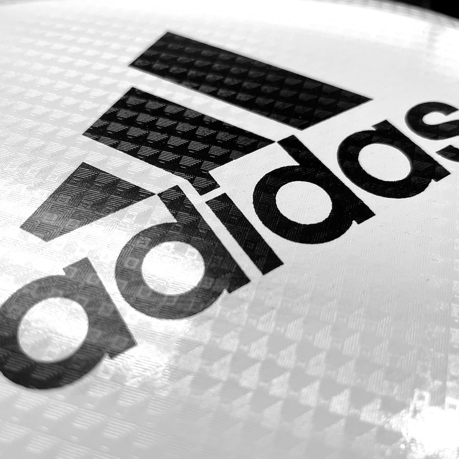 Close-up of Adidas logo on a textured white surface