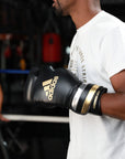 A man wearing Adidas boxing gloves for boxing and kickboxing.