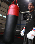 Man wearing boxing gloves holding a punching bag.