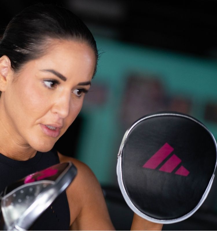 Woman holding a boxing mirror with Adidas logo