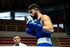 Man in boxing ring with blue adidas Combat Sports boxing gloves. Referee in background. 