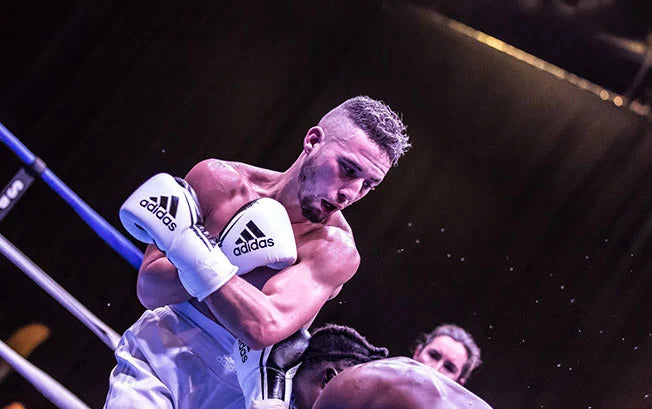 Boxer in the ring during a match holding his adidas gloves in front of his chest.