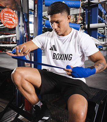 Boxer wrapping his hand with blue wrist bandages.