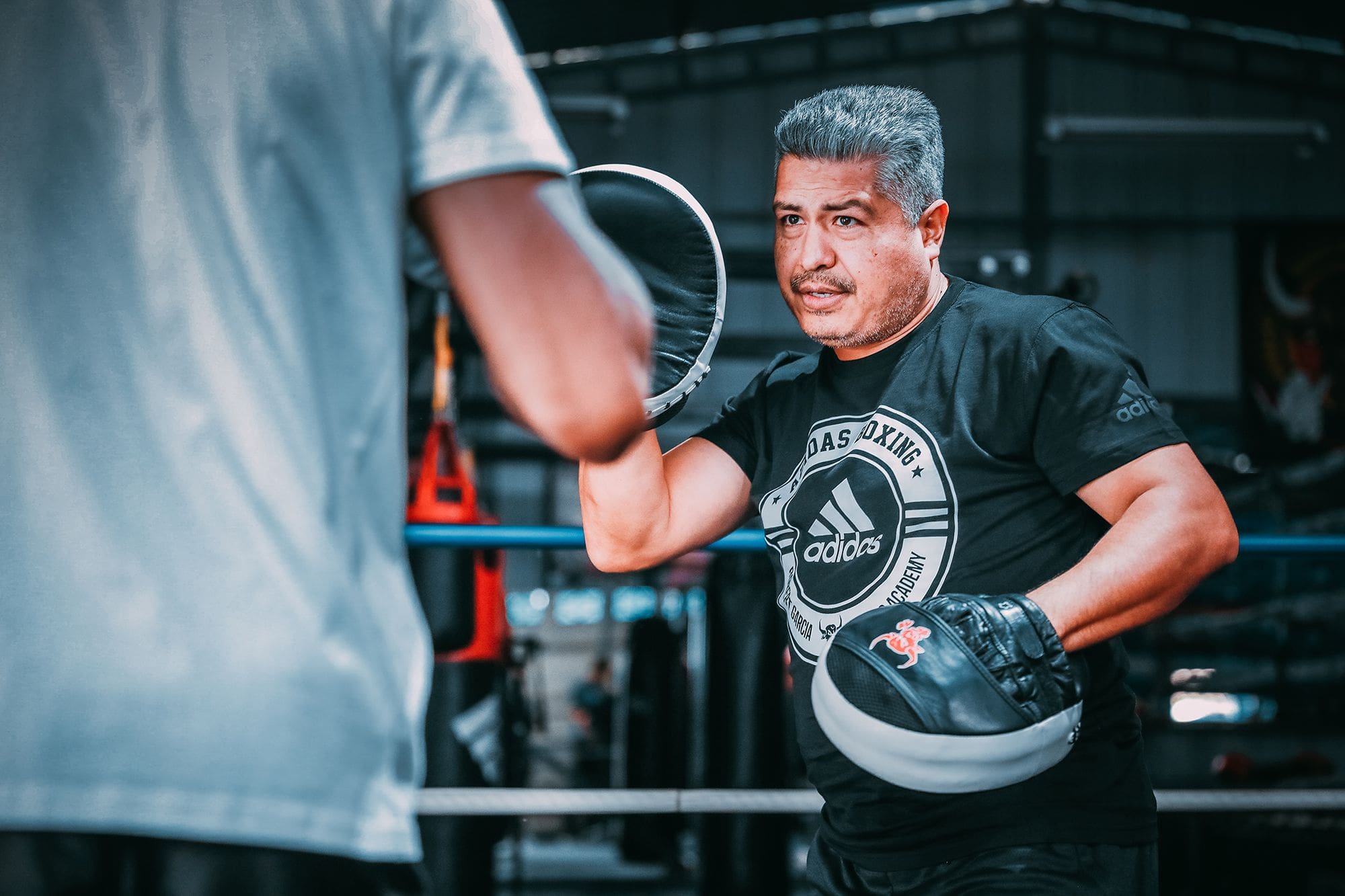 Man inside a boxing ring wearing boxing gloves.