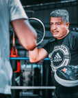 Man inside a boxing ring wearing boxing gloves.