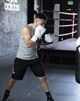 Man standing in a boxing ring wearing gloves.