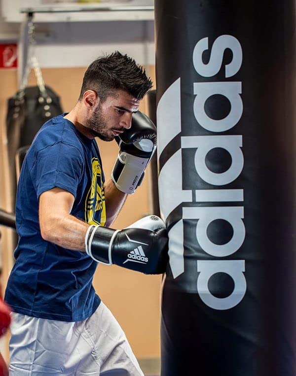 Man wearing boxing gloves punching a bag in action.