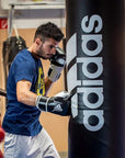 Man wearing boxing gloves punching a bag in action.