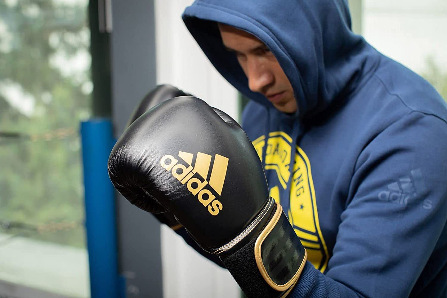 Man wearing hoodie and boxing gloves focusing on technique.