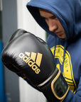 Man wearing hoodie and boxing gloves focusing on technique.