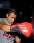 A man punching a heavy punching bag wearing gloves.