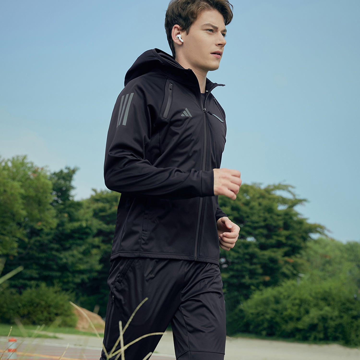 Man running in a black jacket from adidas Men&#39;s Hydrosuit adiSS23.