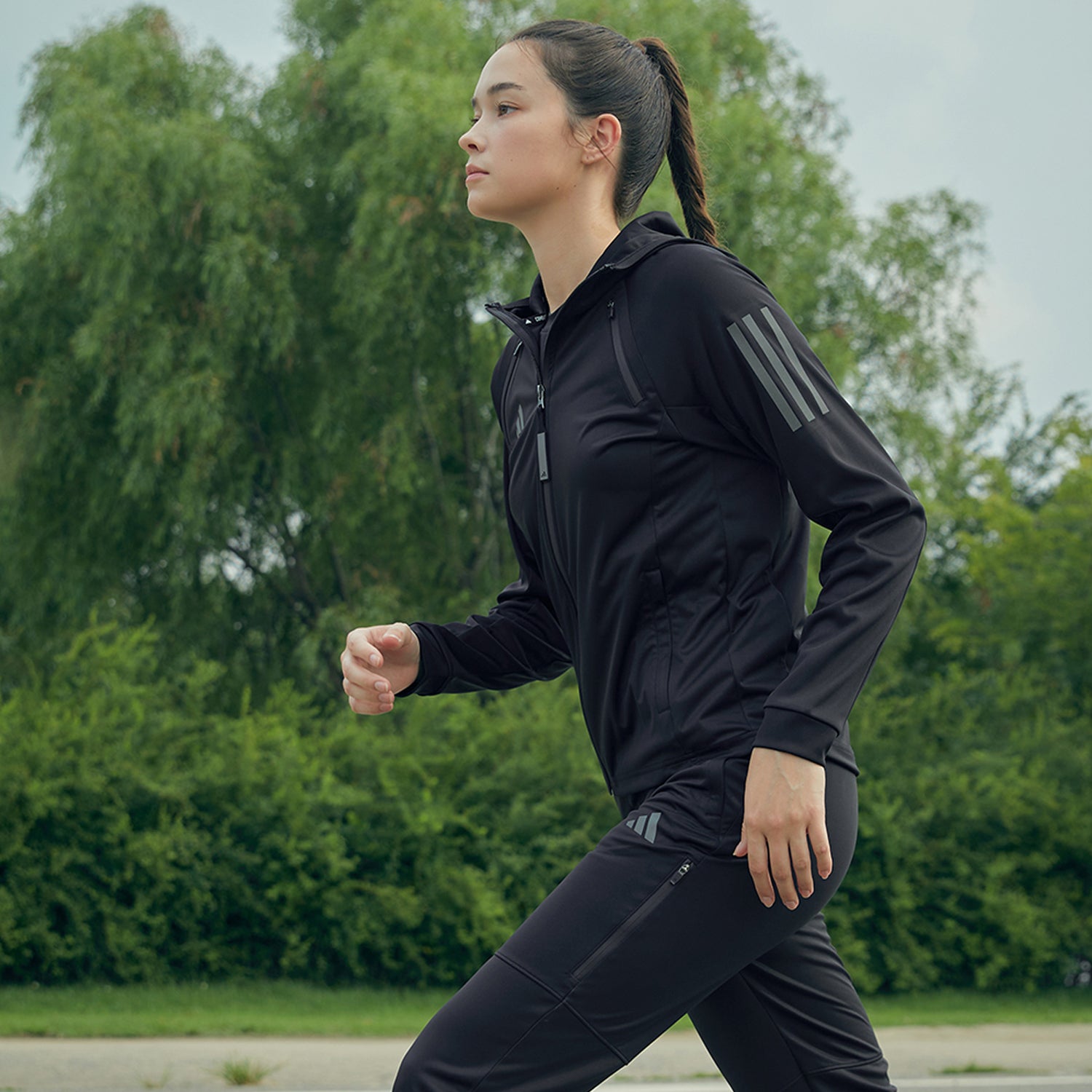 A woman in black running, wearing adidas Women&#39;s Hydrosuit.