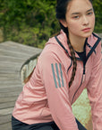 Woman sitting on wooden surface wearing pink apparel.