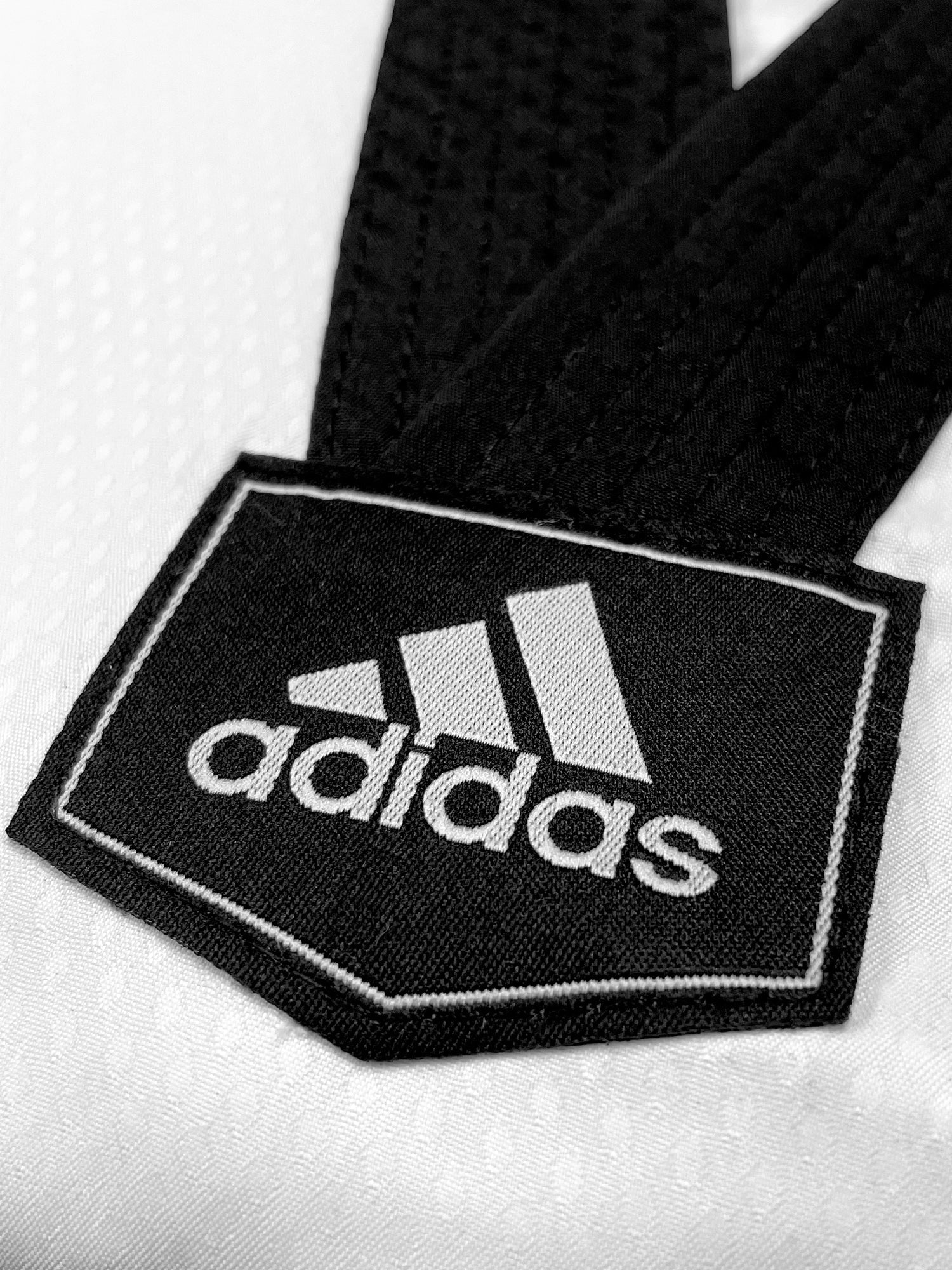 Black and white logo on a black belt with Adidas branding.