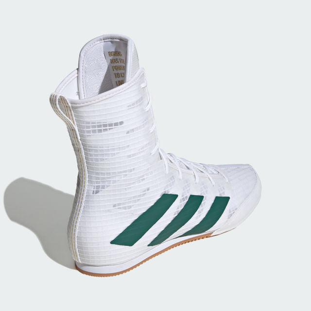 White Adidas boxing shoe with green stripes on a light gray background