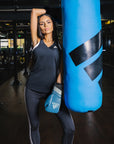 Woman with boxing gloves near a punching bag.