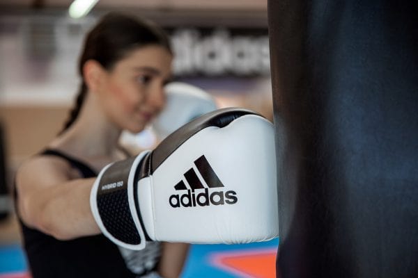 A woman wearing adidas Hybrid 150 boxing gloves.