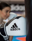 A woman wearing adidas Hybrid 150 boxing gloves.