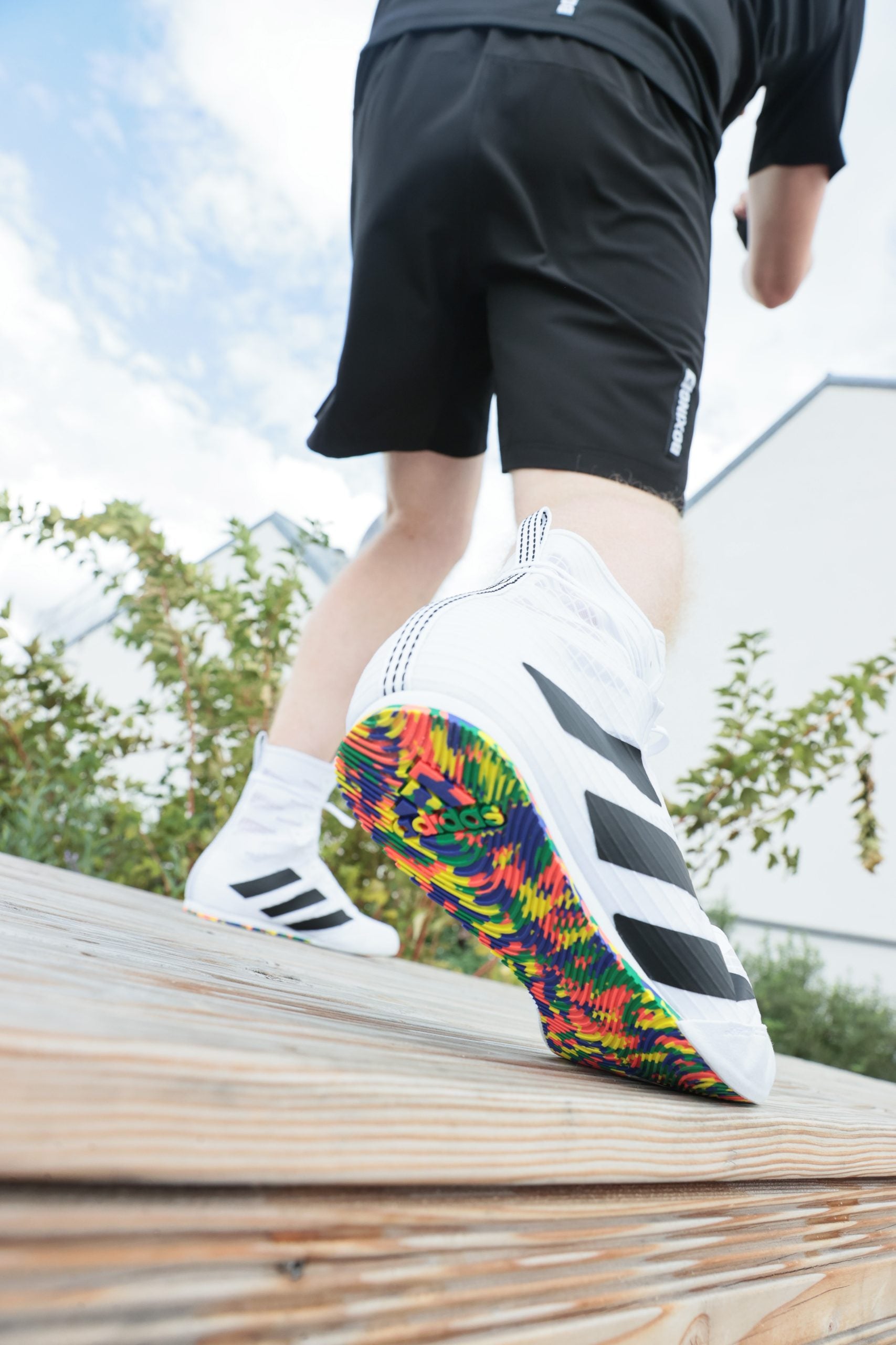 Person wearing shorts with white running shoes.