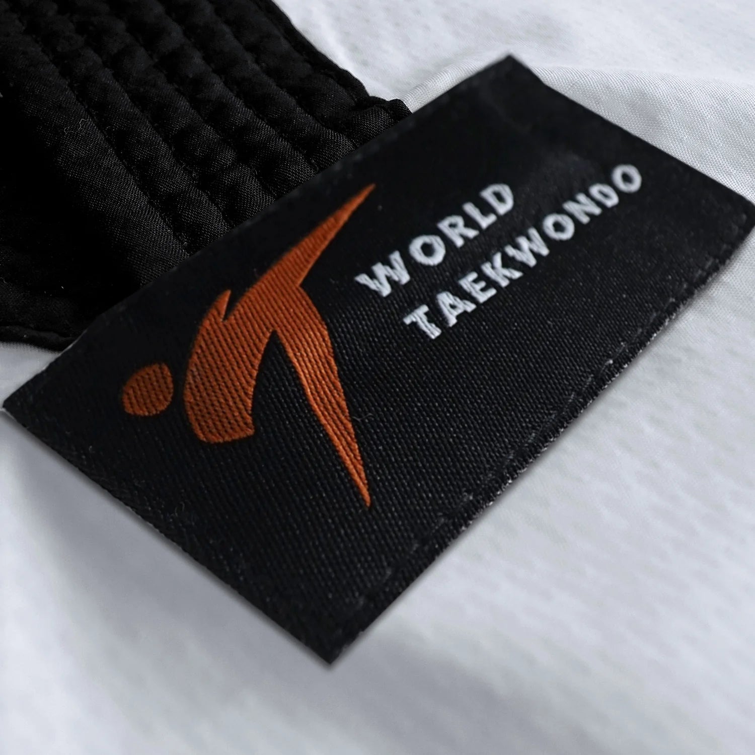 Black and orange tag on a white fabric from adidas Taekwondo Eco Fighter Uniform.