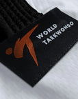 Black and orange tag on a white fabric from adidas Taekwondo Eco Fighter Uniform.