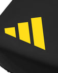 Close-up of black Adidas x Anderson Silva thigh pad featuring yellow logo for MMA training.