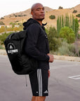 A man wearing a backpack in a parking lot, no clear connection to product.