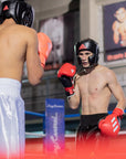 Two men wearing boxing gloves and helmets in a match.