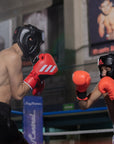 Two men wearing boxing gear and helmets for training.