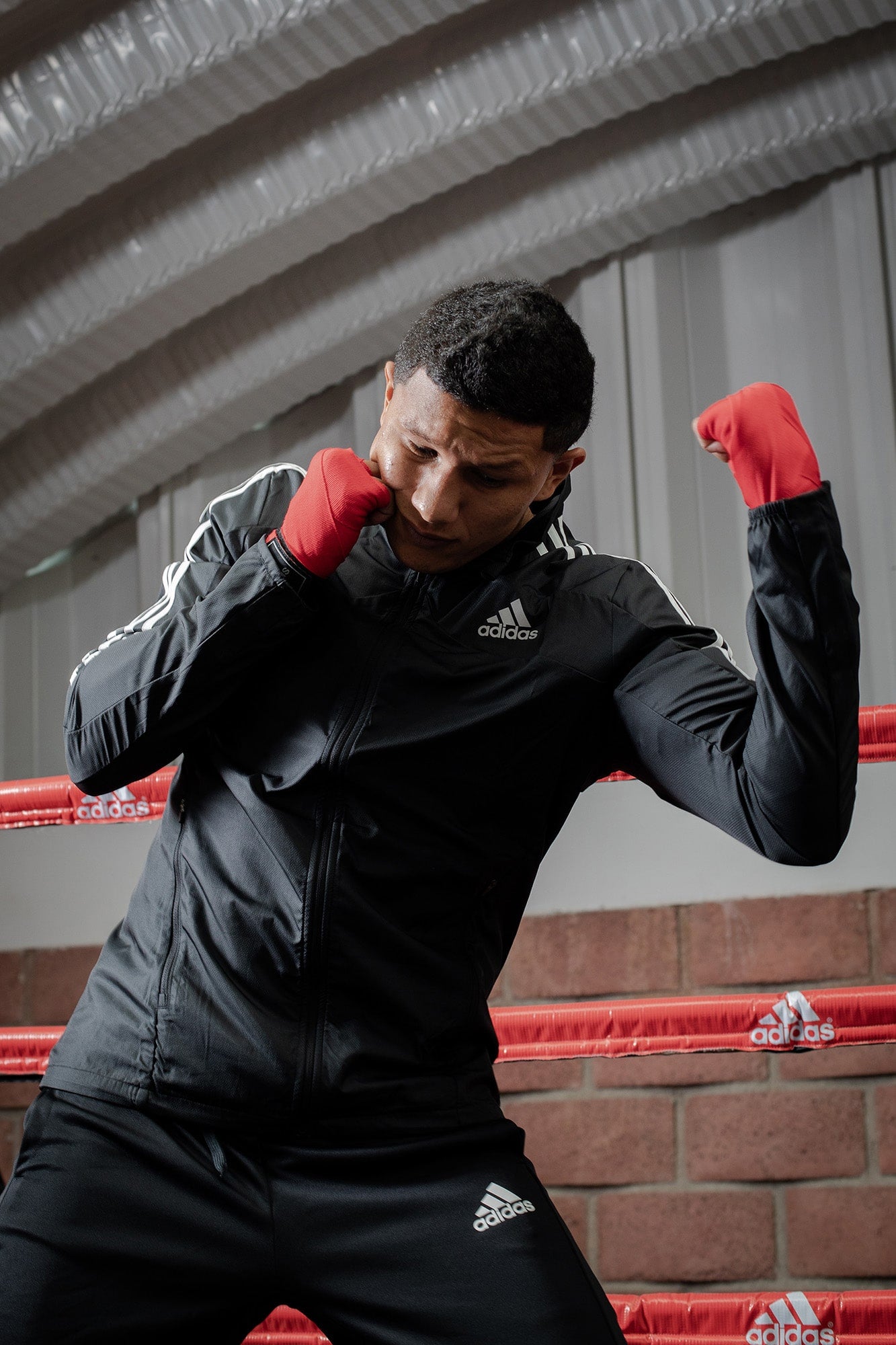 Man standing in a boxing ring with hand wraps.