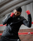 Man standing in a boxing ring with hand wraps.