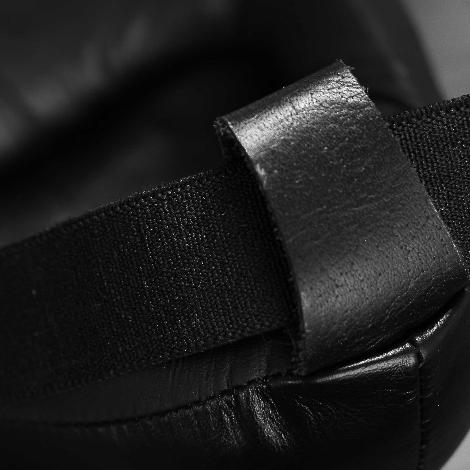 Black strap on a boxing glove, part of groin guard equipment.