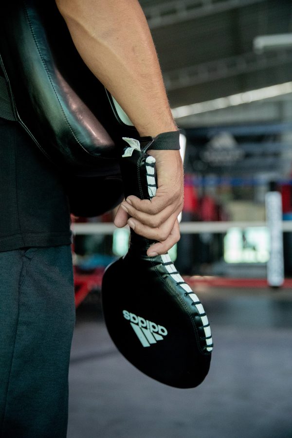 Person holding a boxing glove for adidas paddle target.