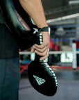 Person holding a boxing glove for adidas paddle target.