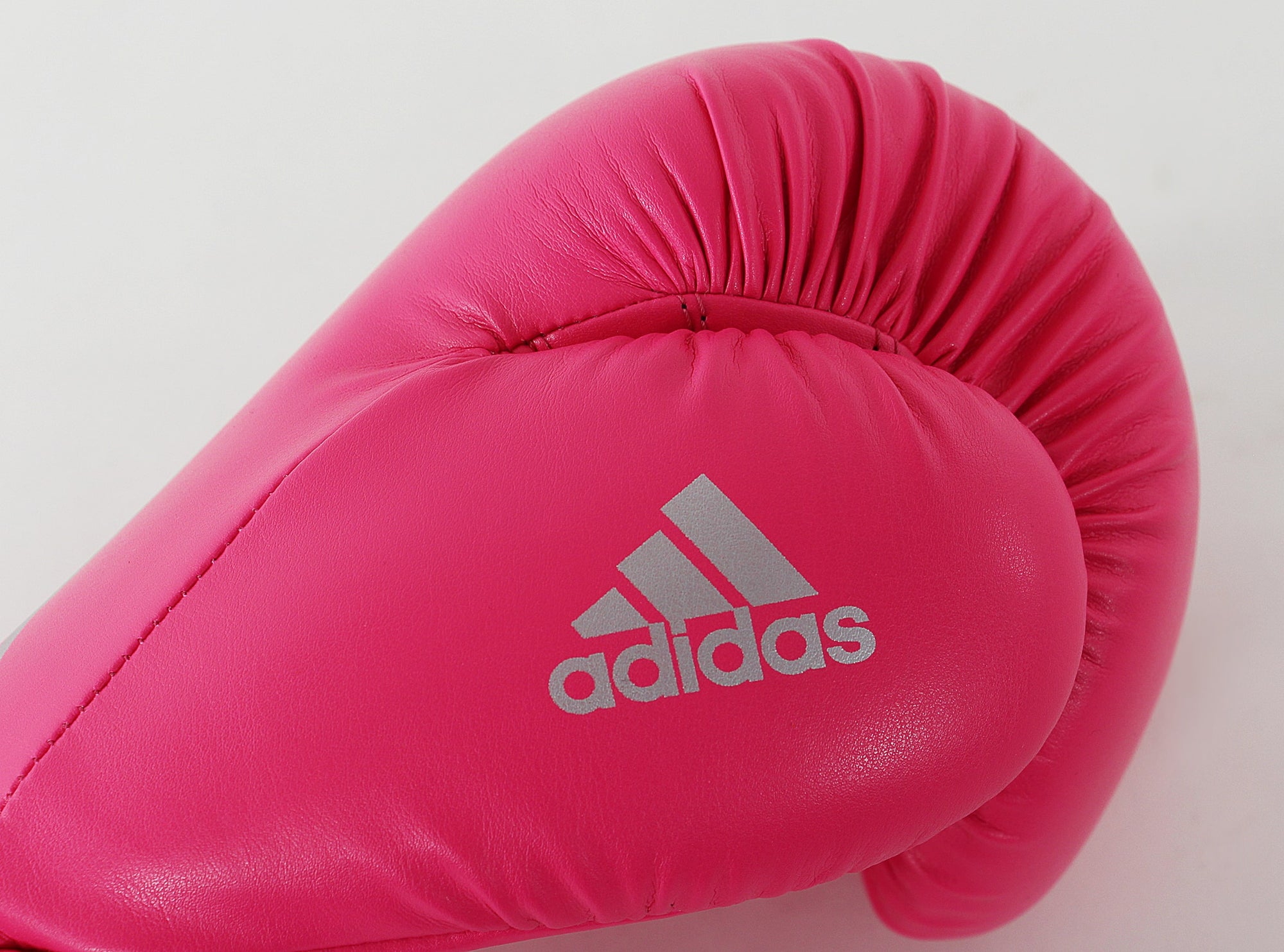 Pink boxing glove showcasing adidas logo.