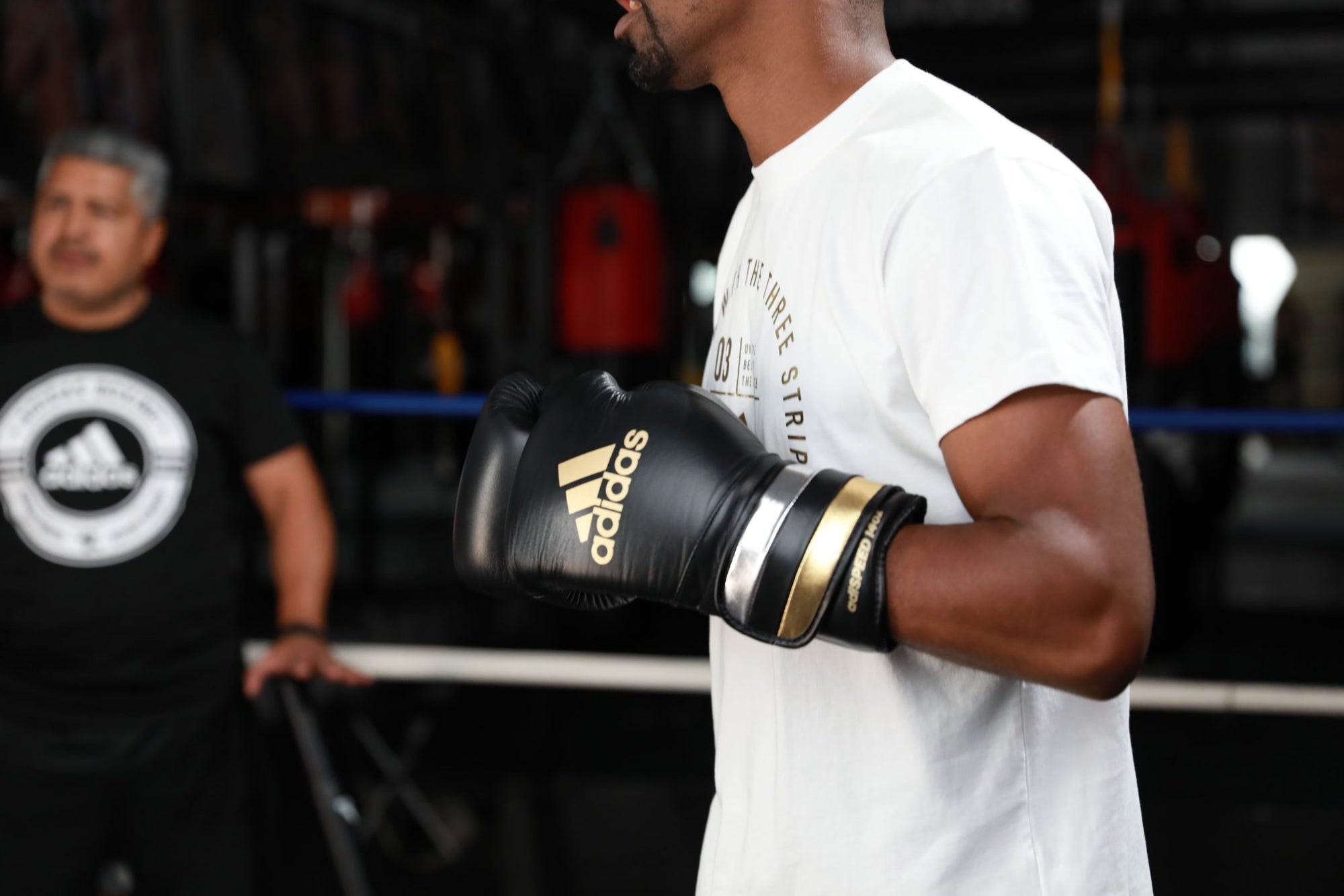 A man wearing Adidas boxing gloves for boxing and kickboxing.