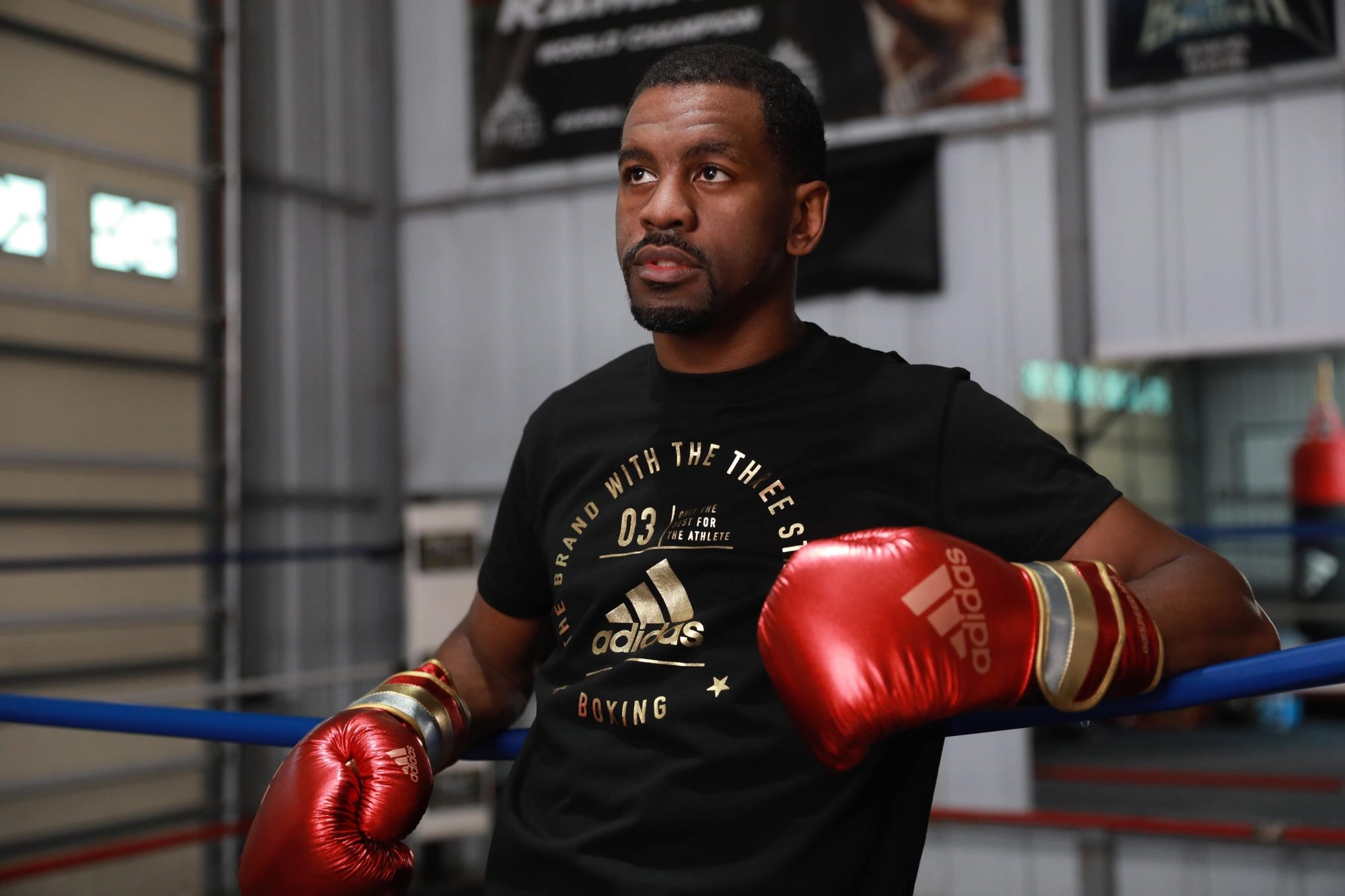 A man wearing red, gold, silver adidas boxing gloves.