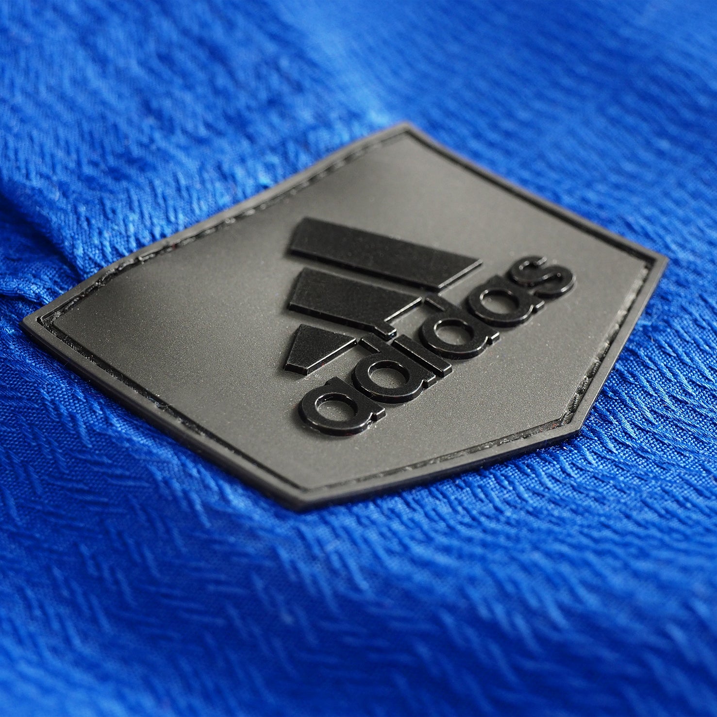 Black logo on blue fabric for Adidas Champion Taekwondo uniform.