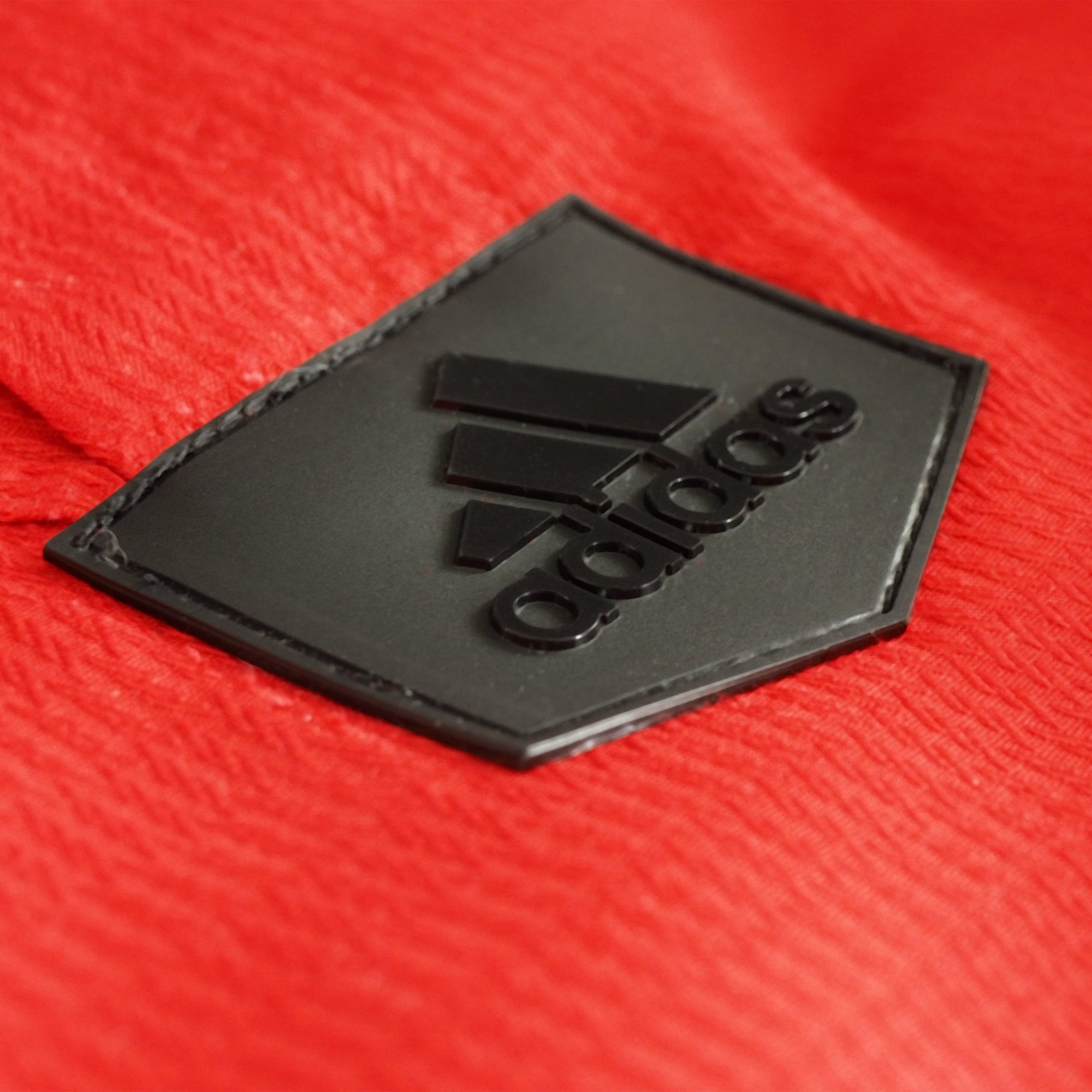 Black logo on red fabric for Adidas Champion Taekwondo uniform.