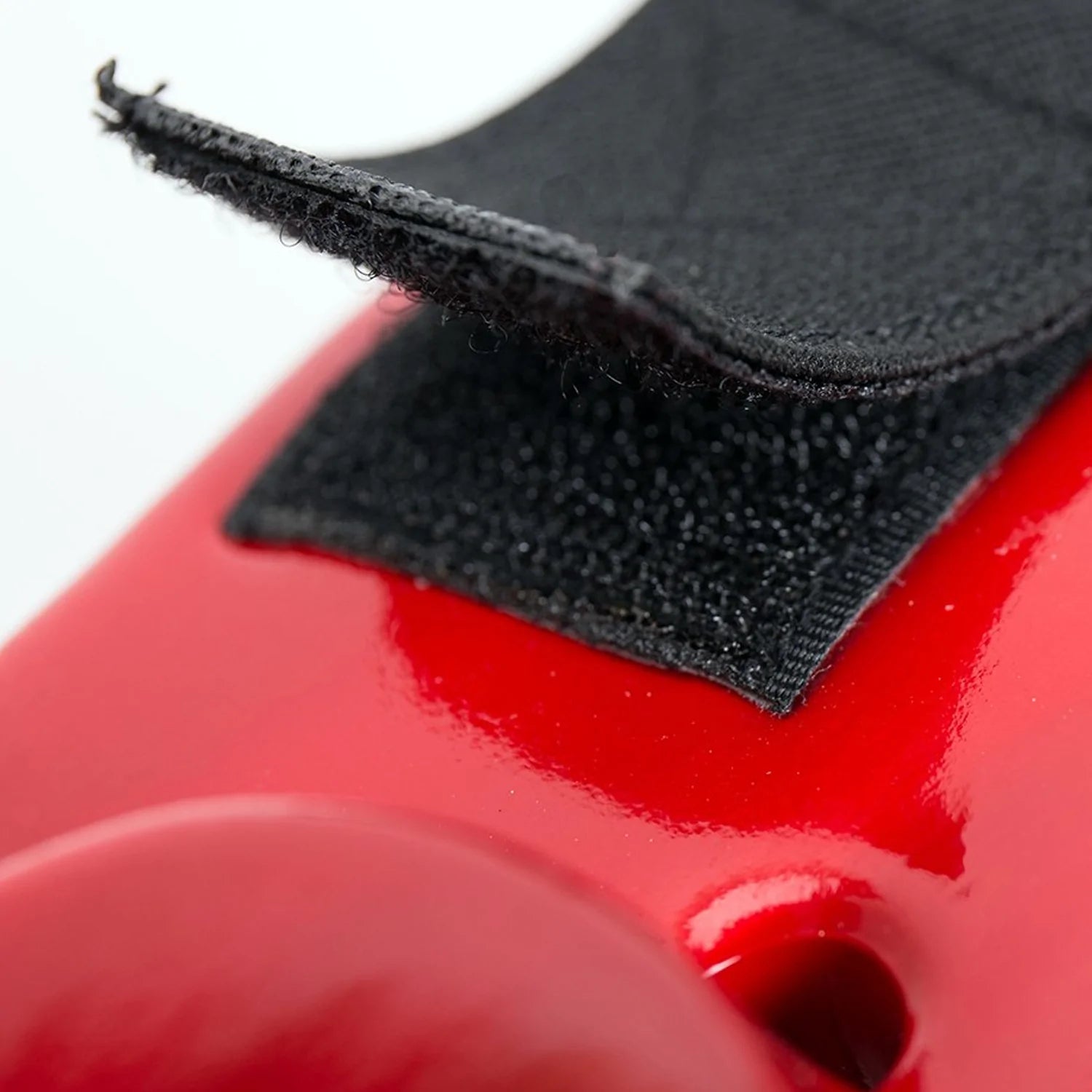 Black velcro strap on a red head guard for secure fit.