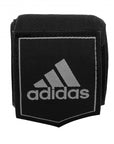 Black wrist band with white adidas logo, for boxing protection.