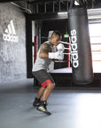 Man wearing boxing gloves punching a punching bag.