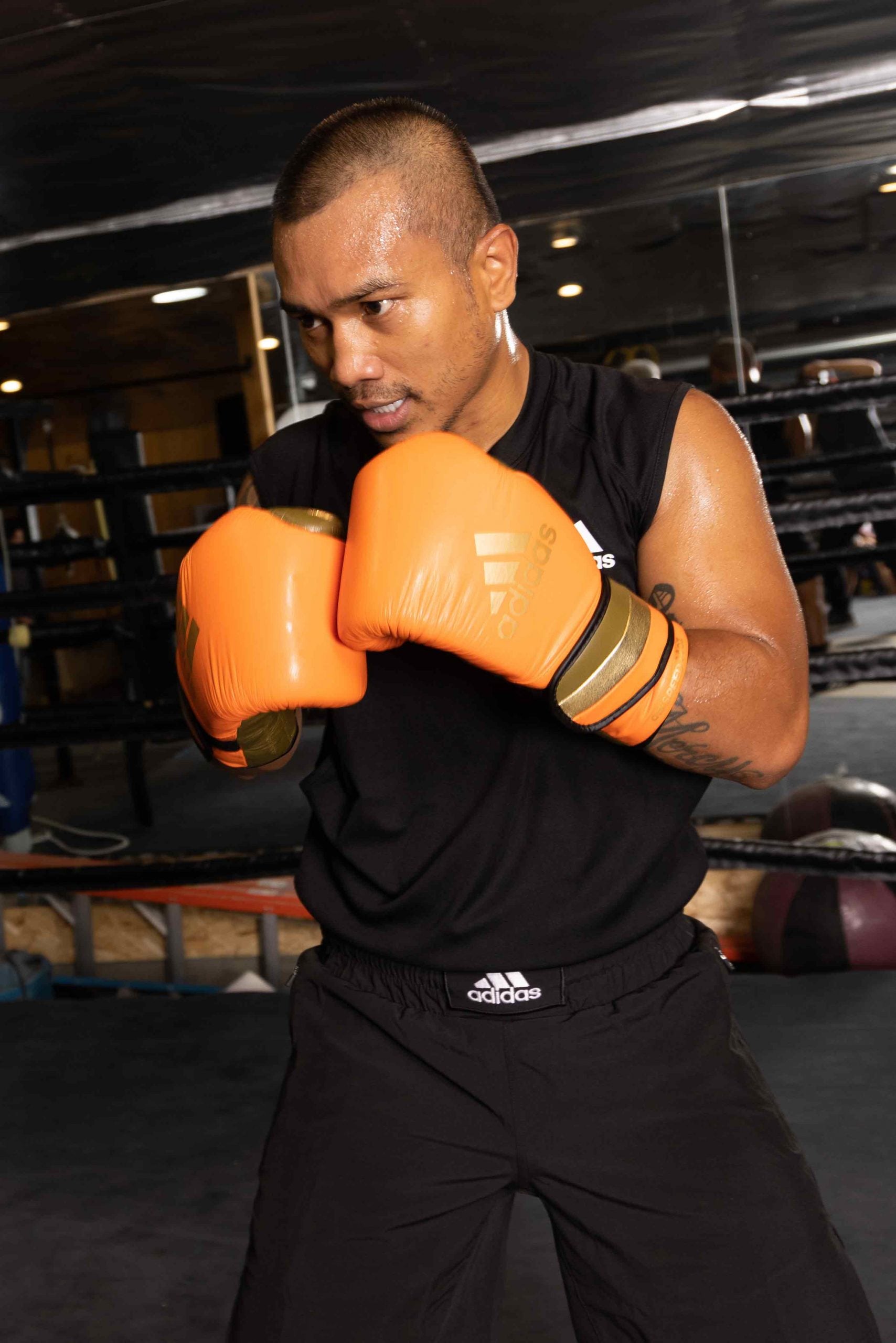 A man wearing adiSPEED 501 PRO boxing gloves.