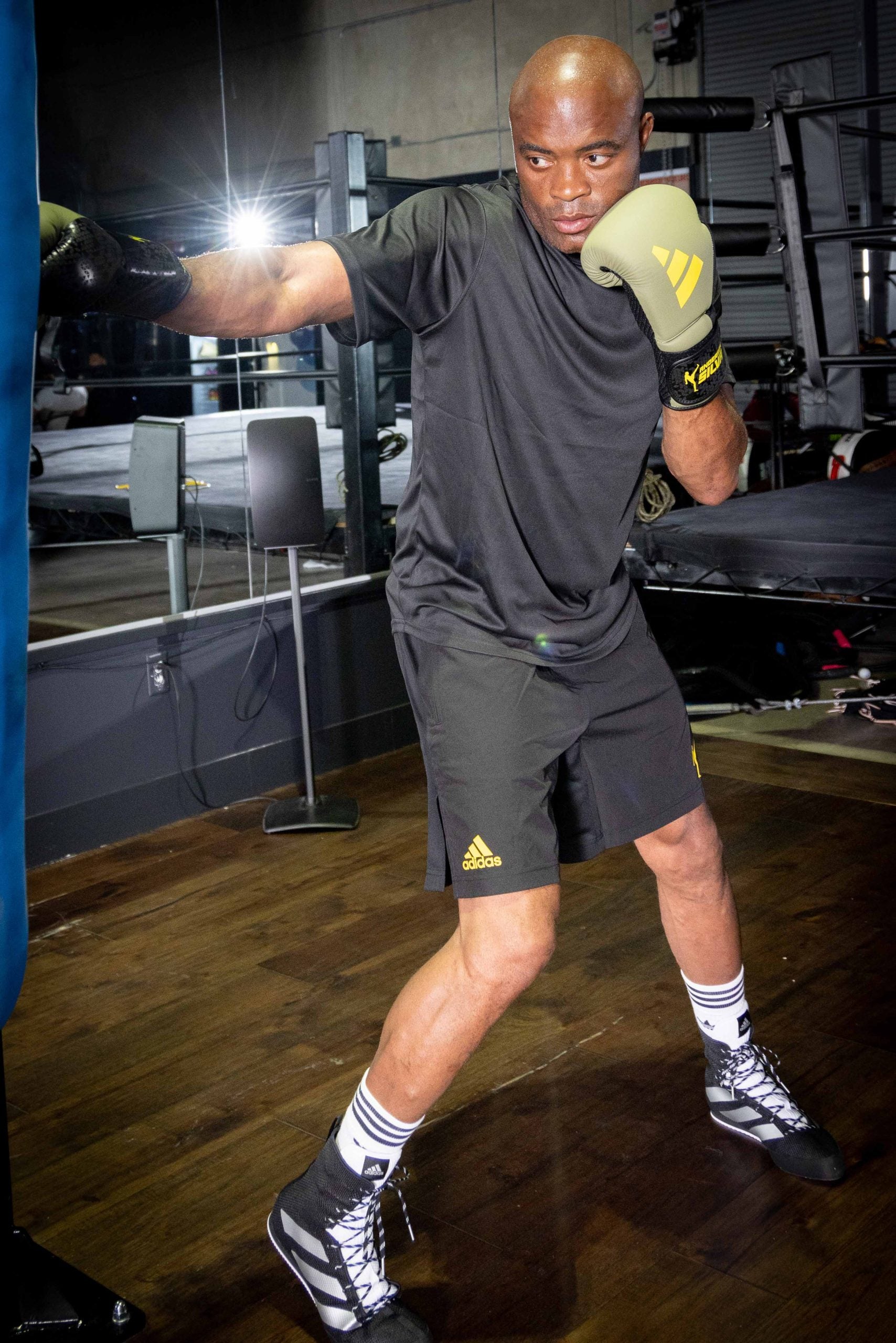 Man wearing boxing gloves in Adidas training shorts.